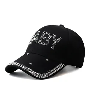 Close-up of sparkling rhinestone BABY letters and studded brim on black baseball cap