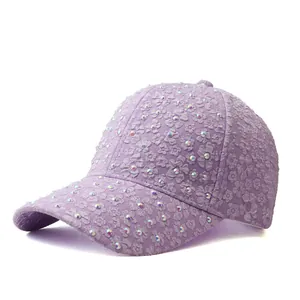 Détail de broderies florales et de strass colorés sur une casquette de baseball violet clair