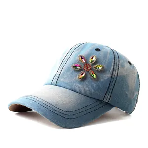 Close-up of rainbow rhinestone floral pattern on light blue denim baseball cap