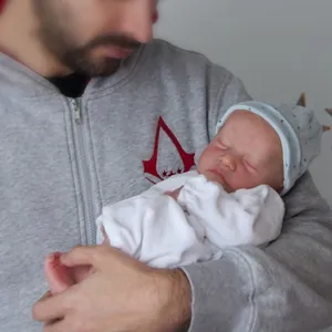 Bambola reborn dormiente realistica da 19 pollici in tutina bianca, tenuta in braccio