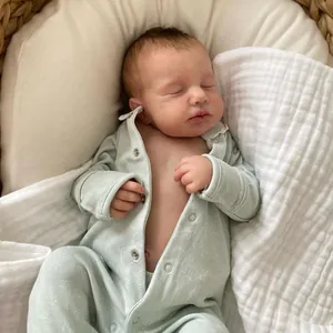 Reborn baby doll LOULOU in mint floral romper resting in a rustic wicker basket