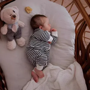 19-inch lifelike newborn baby doll wearing black and white striped romper in a woven cradle