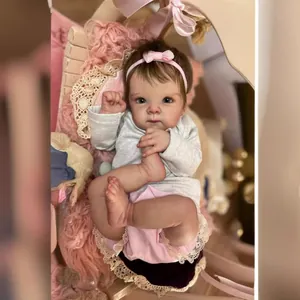 Realistic 18 inch reborn baby doll with pink headband and lace skirt in a wooden cradle
