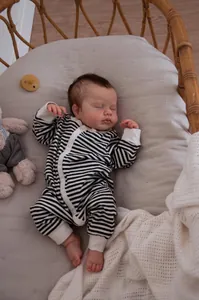 Close-up of 19-inch lifelike reborn baby doll in striped romper inside a wicker basket