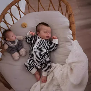 Detailed view of the 19 inch newborn baby doll in a striped romper inside a wicker basket