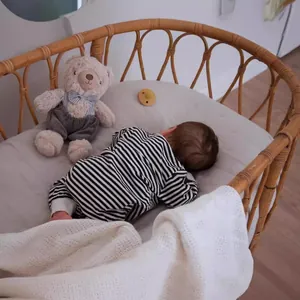 19-inch reborn baby doll Loulou wearing striped onesie in a woven Moses basket