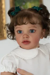 Close-up of 26-inch lifelike toddler doll with curly brown hair and blue eyes in a lace dress