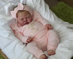 Close-up of realistic newborn doll in pink Queen of Cute outfit and matching headband