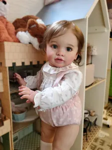 Close-up of Reborn Baby Doll Pippa with curly hair and blue eyes in floral outfit