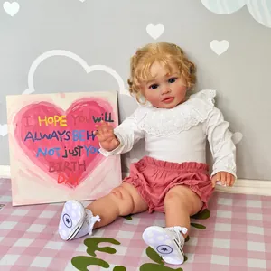 Lifelike 26-inch reborn baby doll Pippa with blonde curls and pink outfit in a cozy room