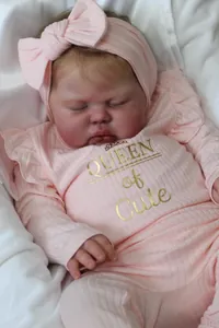 Close-up of lifelike reborn doll face wearing pink Queen of Cute ribbed outfit