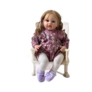 Lifelike 60cm reborn doll with blonde curls, blue eyes and purple floral dress in sitting pose