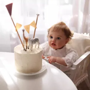 60cm lifelike reborn baby doll with brown curly hair and lace outfit in a high chair