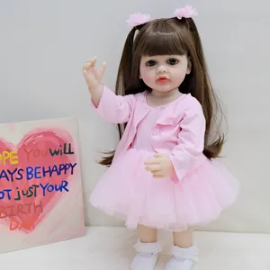 Detalle de muñeca reborn Betty de 55cm con coletas marrones y cárdigan de punto rosa