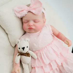 Gros plan d'une poupée Reborn réaliste de 48cm en robe rose avec ours au crochet