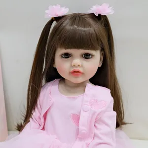 Detalle de muñeca reborn con pelo castaño, pinzas de flores rosas y cárdigan bordado de corazón
