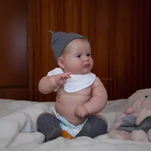 Detailed view of a 50cm lifelike reborn baby doll in knit hat, bib and socks on a soft rug