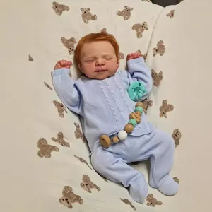 Lifelike 19-inch reborn baby doll in light blue knit outfit with closed eyes sleeping