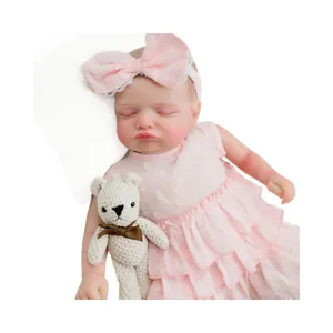 Poupée Reborn Rosalie en robe rose à pois tenant un petit ours en tricot