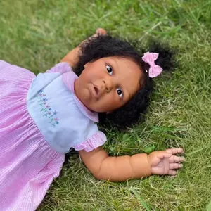 Muñeca reborn realista de 60cm con vestido de cuadros rosa sobre césped verde