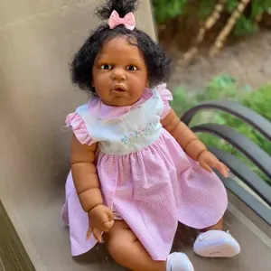 Detalle macro de muñeca Reborn negra de 60cm con vestido rosa en silla de mimbre