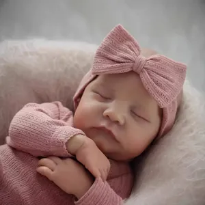Lifelike 19 inch reborn baby doll wearing pink ribbed knit outfit and bow headband