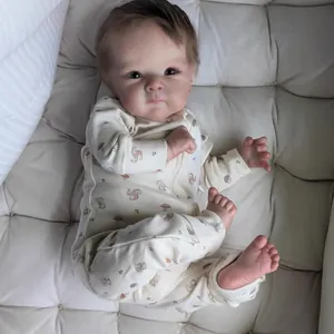 Close-up of realistic newborn baby doll in squirrel print onesie on white quilted pad