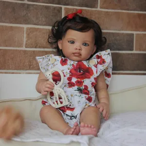 Reborn baby girl doll Reuben with curly hair and poppy floral romper and giraffe toy