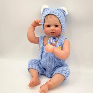 Realistic 49cm Elijah reborn baby doll wearing a blue handmade knit outfit on white background