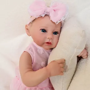 Realistic 49cm Raven reborn baby doll in pink lace dress on soft beige pillow