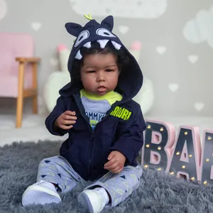 Reborn baby doll Liam with curly black hair wearing blue monster hoodie and gray trousers