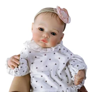 Realistische reborn babypop Meadow 46cm met witte hartjesjurk en bloemen hoofdband