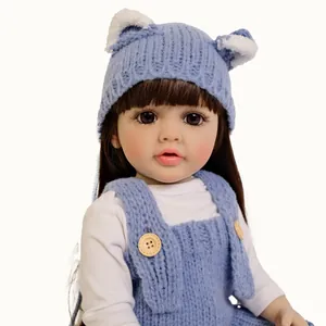 Poupée Betty réaliste de 55cm avec salopette en tricot bleu et bonnet d'ours sur fond blanc