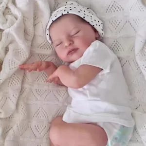 Realistic 19-inch reborn sleeping baby doll in white polka dot hat on woven blanket