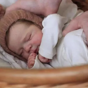 50cm lifelike reborn baby doll in knit hat and white top resting in a woven basket