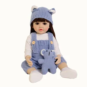 Poupée réaliste Betty de 55cm avec cheveux bruns, salopette bleue tricotée et bonnet ours