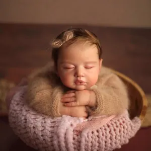 Realistic 19-inch sleeping reborn baby doll in brown sweater on pink knit blanket