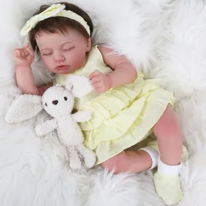 Gros plan d'une poupée reborn endormie en robe jaune à pois avec lapin en peluche