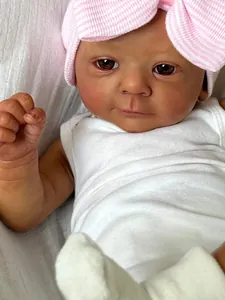 Macro shot of 18-inch realistic baby doll featuring detailed skin texture and pink bow hat