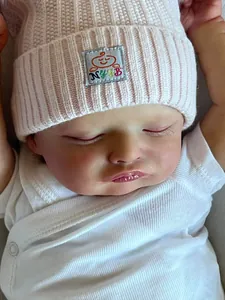Gros plan d'un visage de poupée Reborn endormie avec texture réelle et bonnet rose