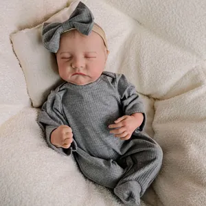 Realistic 18-inch newborn doll in grey knitted romper with matching headband on soft cushion