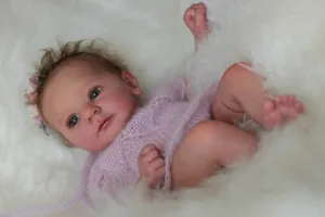 Close-up of 18 inch realistic reborn doll with pink knit outfit and flower headband