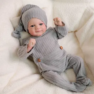 Lifelike 18-inch Reborn baby doll in grey knitted romper and hat on a soft background