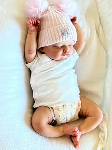 Vue détaillée d'une poupée Reborn de 18 pouces avec bonnet rose et couche à fleurs sur lin