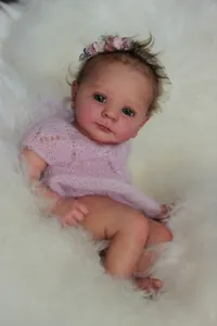Detail of 18-inch reborn baby doll featuring pink knitted dress and floral headband
