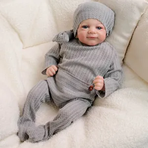 Realistic 18-inch reborn baby doll in grey waffle knit outfit with blue eyes on soft cushion