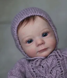 Gros plan d'une poupée reborn réaliste en tenue tricotée violette et chapeau