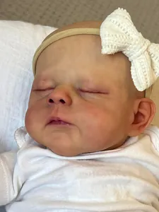 Gros plan du visage endormi d'une poupée Reborn de 19 pouces avec bandeau blanc tricoté