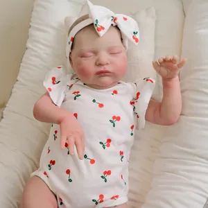 Lifelike 19-inch reborn baby doll Laura in cherry print outfit sleeping in a crib