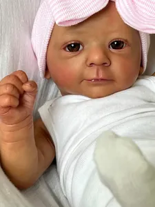 Close-up of a lifelike 18 inch dark skin reborn baby doll wearing a pink bow hat